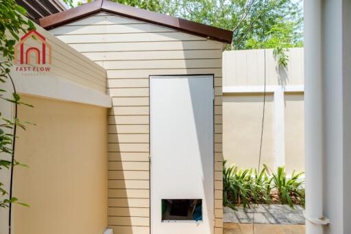 Small backyard storage shed with beige siding and a brown roof.