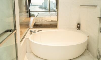 Luxury bathroom with a bathtub and a view of the bedroom and city skyline