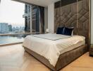 Modern bedroom with a large bed and city view through the window