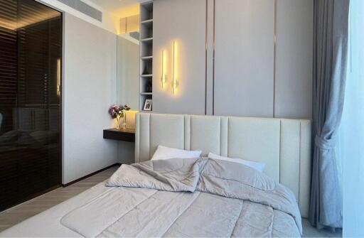 Modern bedroom with minimalist design featuring a large bed, built-in vanity, and soft lighting