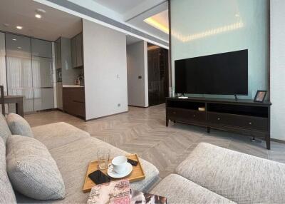 Modern living room with corner sofa, TV unit, and open kitchen