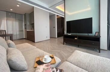 Modern living room with corner sofa, TV unit, and open kitchen