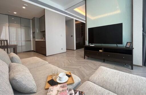 Modern living room with corner sofa, TV unit, and open kitchen