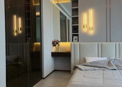 Modern bedroom with plush bed, built-in lighting, and a small vanity area