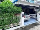 Covered garage with two parked cars and green plant wall