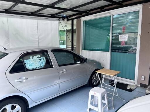 Covered garage with car, table, and chairs