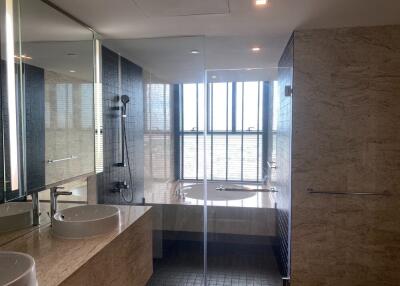 Modern bathroom with twin sinks, glass-enclosed shower, and a bathtub with a large window