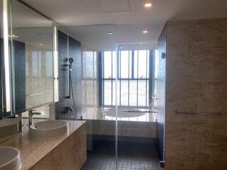 Modern bathroom with twin sinks, glass-enclosed shower, and a bathtub with a large window