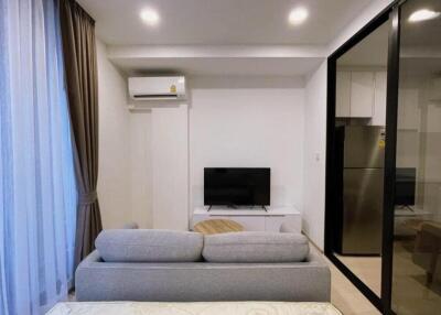 Modern living room with TV, air conditioner, and kitchen view