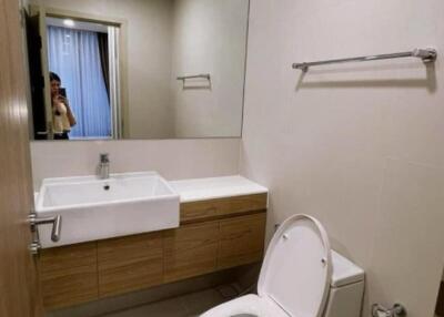 Modern bathroom with sink, mirror, toilet, and towel rack