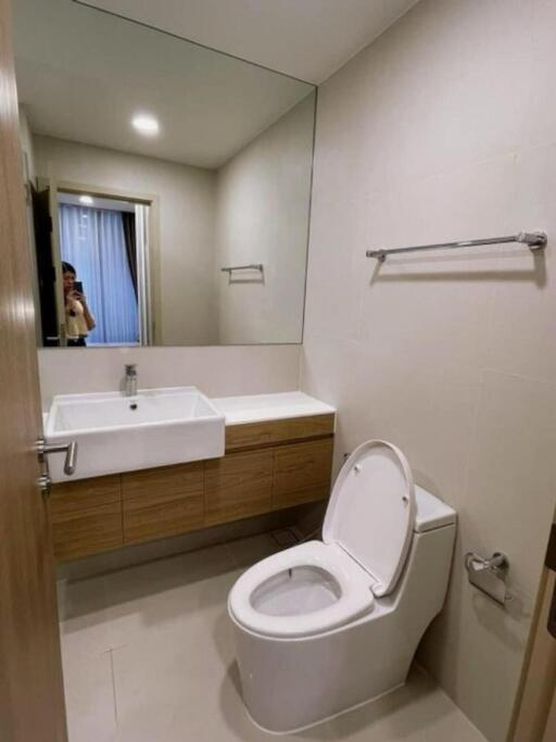 Modern bathroom with sink, mirror, toilet, and towel rack