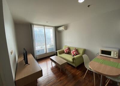 Modern living room with a green sofa, TV, and dining area by a large window