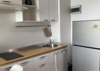 Modern kitchen with white cabinets, stainless steel sink, and fridge