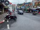 View of a busy street with shops and parked scooters