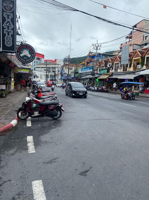 View of a busy street with shops and parked scooters