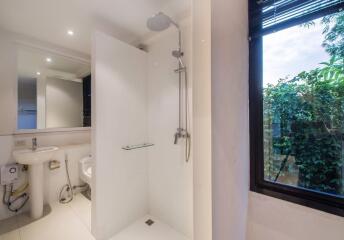 Modern bathroom with walk-in shower, sink, and large window