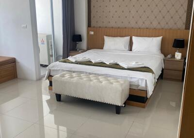 Spacious and modern bedroom with a large bed, bedside tables, an air conditioner, and a dressing table