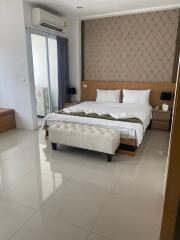 Spacious and modern bedroom with a large bed, bedside tables, an air conditioner, and a dressing table