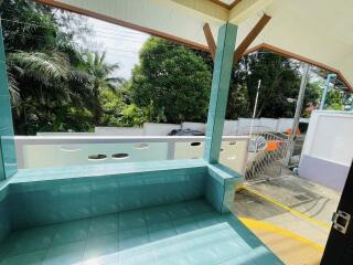 Covered outdoor patio with green tiles and view of driveway