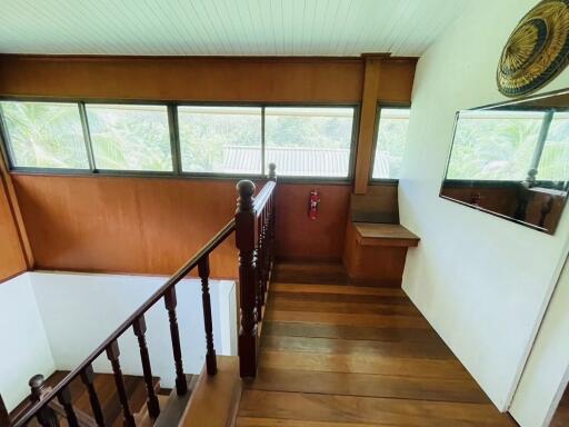 Indoor hallway with wooden stairs and large windows