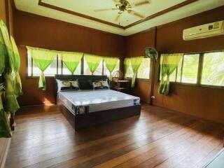 Spacious bedroom with wooden flooring and a large window