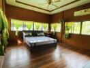 Spacious bedroom with wooden flooring and a large window