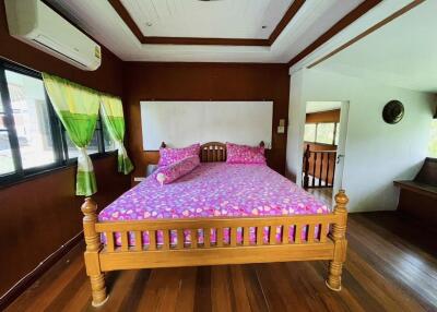 Spacious bedroom with wooden flooring and vibrant decor