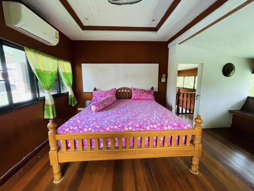 Spacious bedroom with wooden flooring and vibrant decor