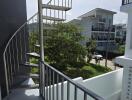 Outdoor spiral staircase with nearby buildings and green area