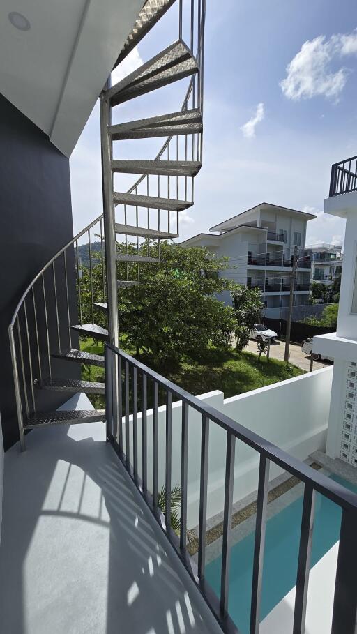 Outdoor spiral staircase with nearby buildings and green area