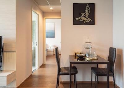 Small dining area with two chairs and a table next to a hallway