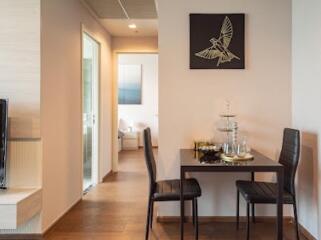 Small dining area with two chairs and a table next to a hallway