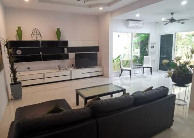 Modern living room with black sofa, ceiling fans, and decorative elements