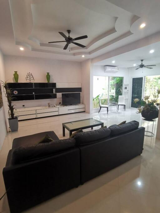 Modern living room with black sofa, ceiling fans, and decorative elements