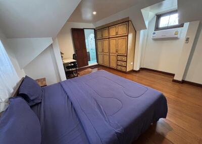 Cozy bedroom with wooden flooring, built-in wardrobe, and air conditioning unit.