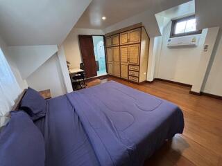 Cozy bedroom with wooden flooring, built-in wardrobe, and air conditioning unit.