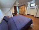 Cozy bedroom with wooden flooring, built-in wardrobe, and air conditioning unit.