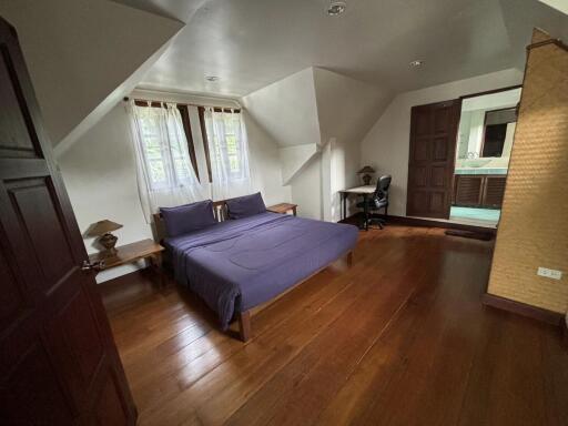 Spacious bedroom with wooden flooring and desk space