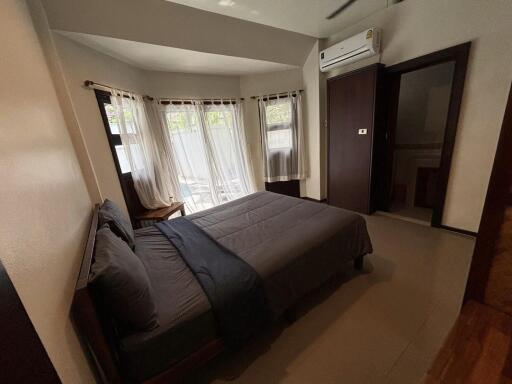 Bedroom with a bed, large windows, air conditioner, and a doorway