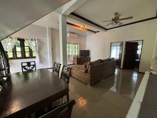 Spacious living room with dining area, television, couches, and modern AC unit