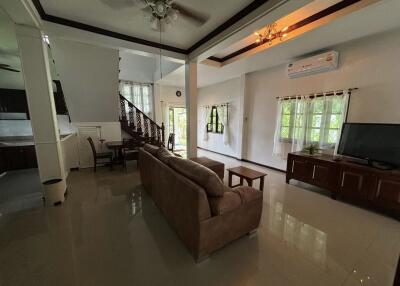 Spacious living room with sofa, TV, dining area, and staircase