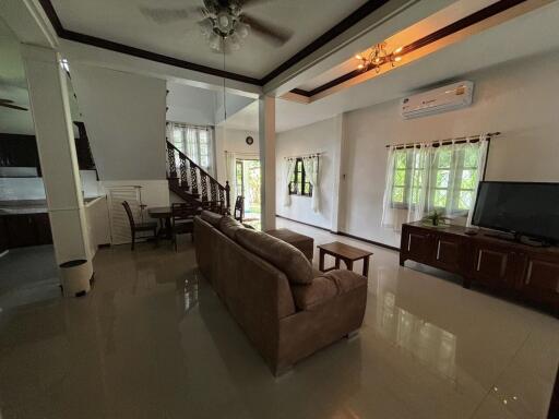 Spacious living room with sofa, TV, dining area, and staircase