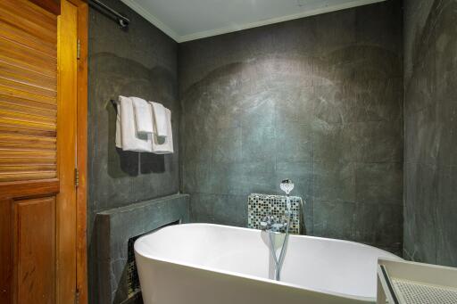 Modern bathroom with a bathtub and dark tile walls