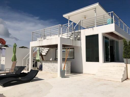 Modern two-story house with rooftop terrace and outdoor seating