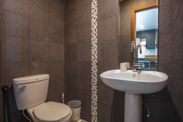 Modern bathroom with dark tiles and a pedestal sink