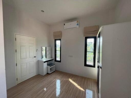 A simple and clean bedroom with wooden flooring and large windows