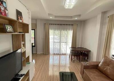 Spacious modern living room with TV, brown leather sofa, and glass coffee table