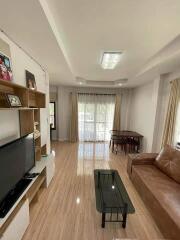 Spacious modern living room with TV, brown leather sofa, and glass coffee table