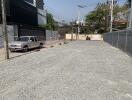 Gravel empty lot with parked vehicle and surrounding buildings