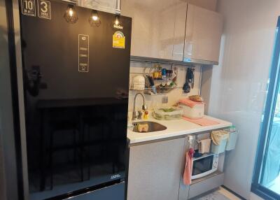 Modern compact kitchen with black refrigerator, sink, cabinetry, and glass sliding door